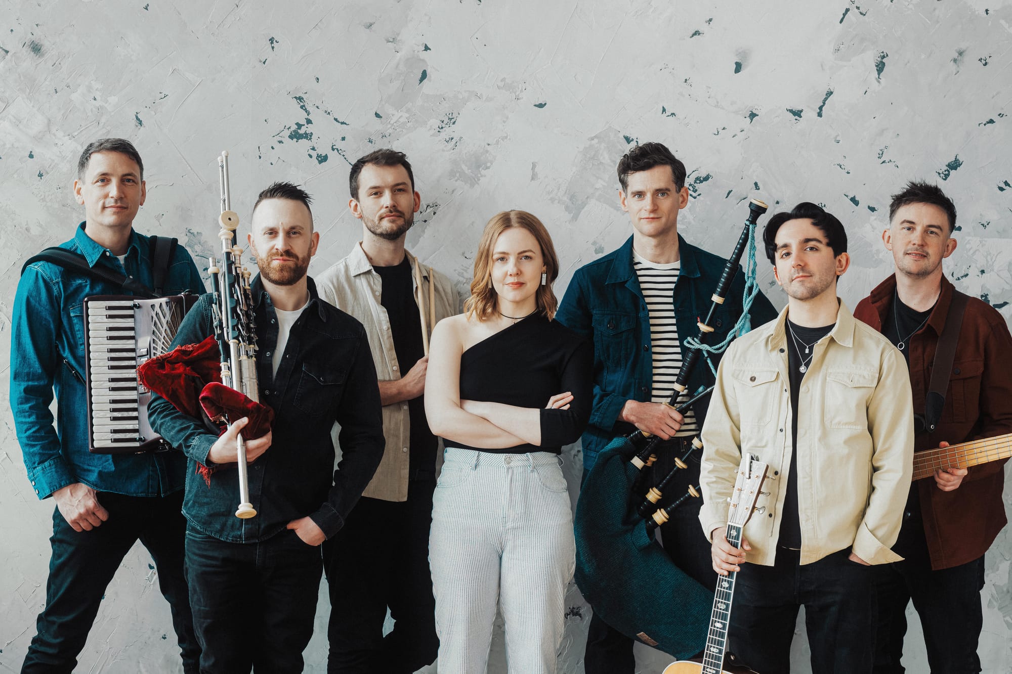 A group of seven people, some holding musical instruments. 