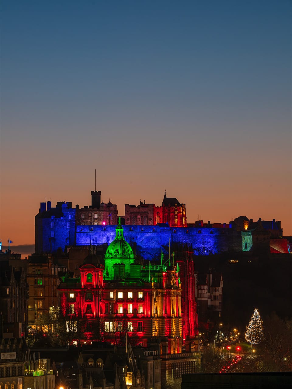 A castle atop a city skyline at sunset. 