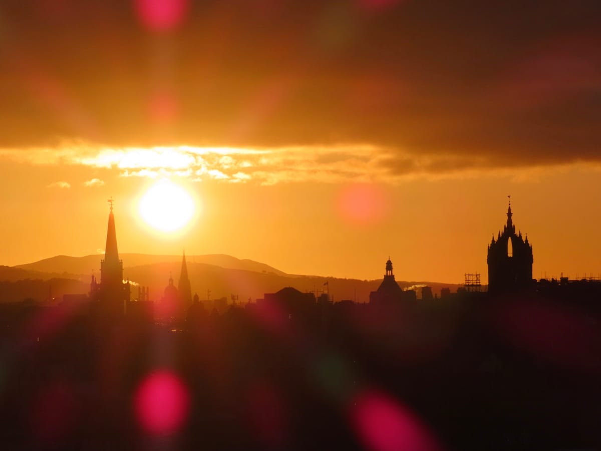 A sun setting behind a city skyline. 