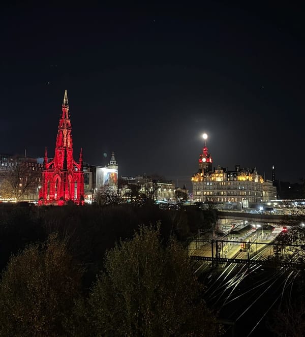 A city at night, with two buildings lit-up red. 