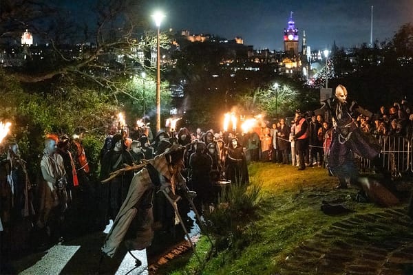People on a hill at night watching a fire display. 