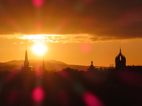 A sun setting behind a city skyline. 
