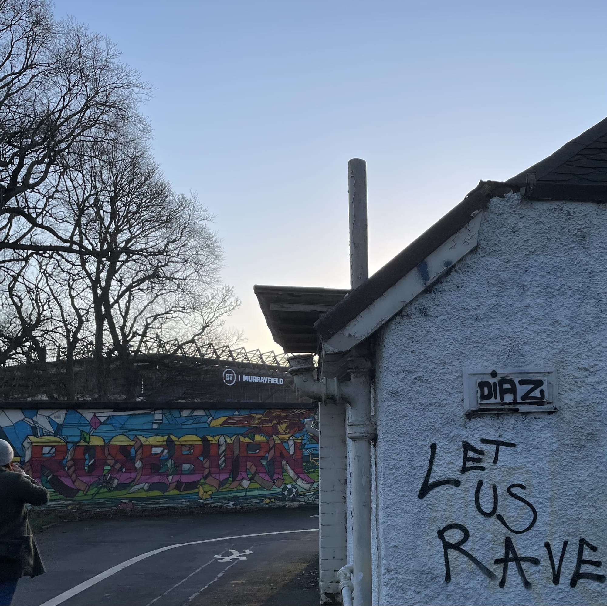 Murrayfield stadium in the background behind graffiti walls with art reading ‘Roseburn’ and ‘let us rave’.